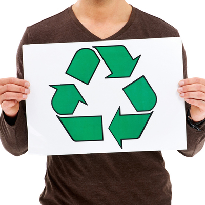 white person in brown shirt, holding white sign with green chasing arrows image