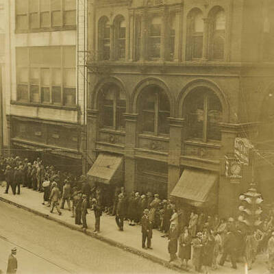 Sepia tone photo of people lined up on a city block