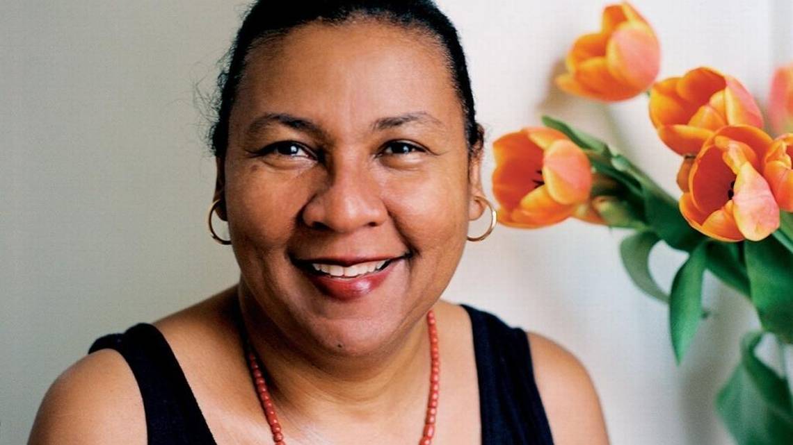 Headshot of writer and feminist critic bell hooks with hair pulled back, wearing a black tank top, red beaded necklace, and gold hoop earrings