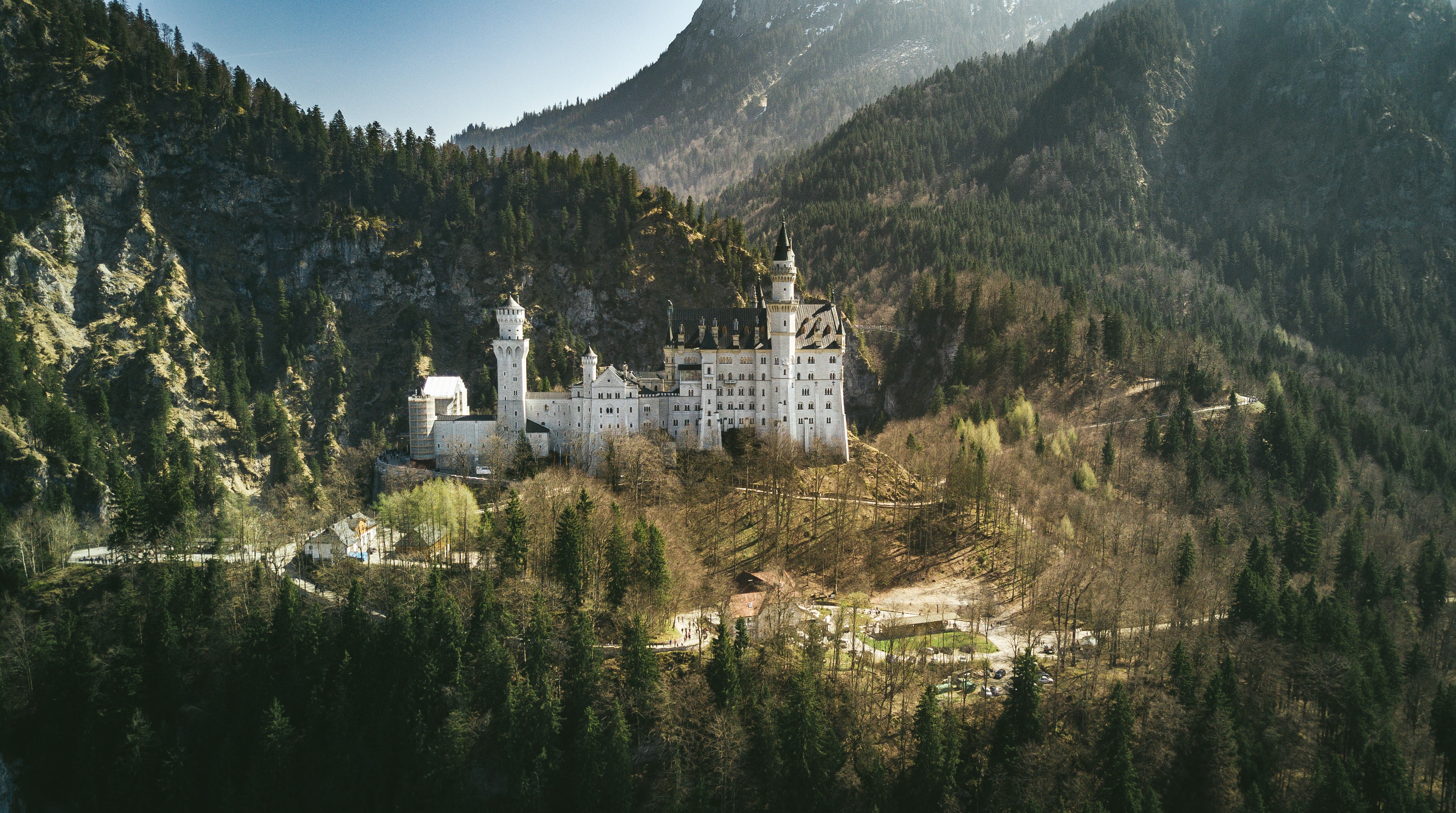 a white castle in the valley of mountains.