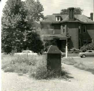 1955 scrapbook photo of a trash can with a fire in it, near Elliston Place