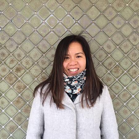 Picture of Children's Book Author and Illustrator Thao Lam. She is a Vietnamese Canadian woman, with long brown hair and sideswept bangs. She is wearing a scarf tucked into a seemingly very light gray coat. 