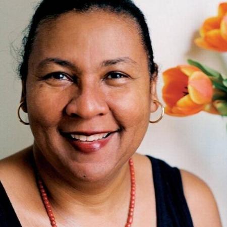 Headshot of writer and feminist critic bell hooks with hair pulled back, wearing a black tank top, red beaded necklace, and gold hoop earrings